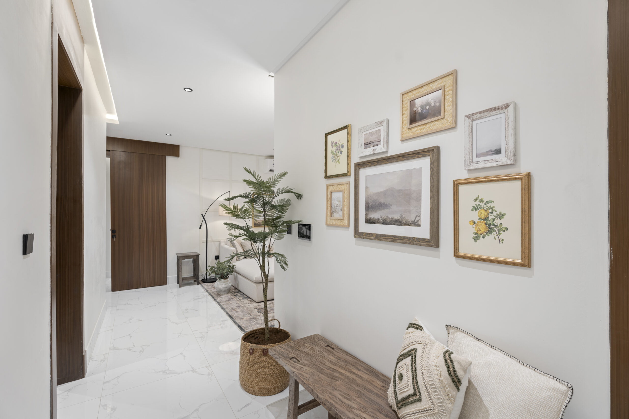 hallway with painting on the wall and plants on floor