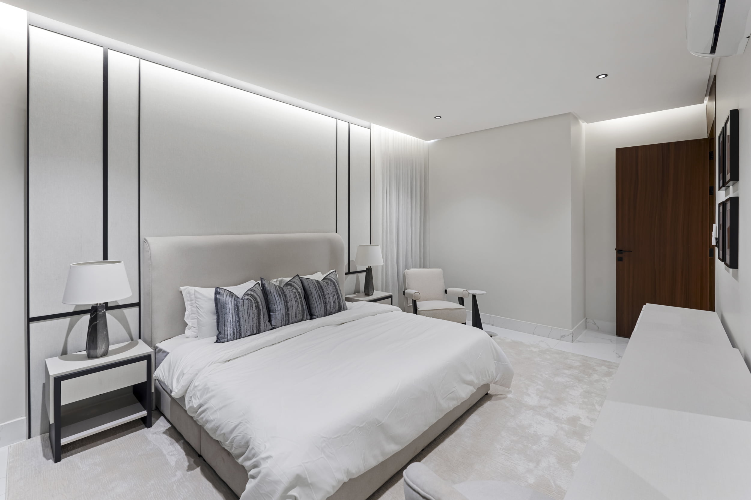 white master bedroom with black pillows and wooden doors
