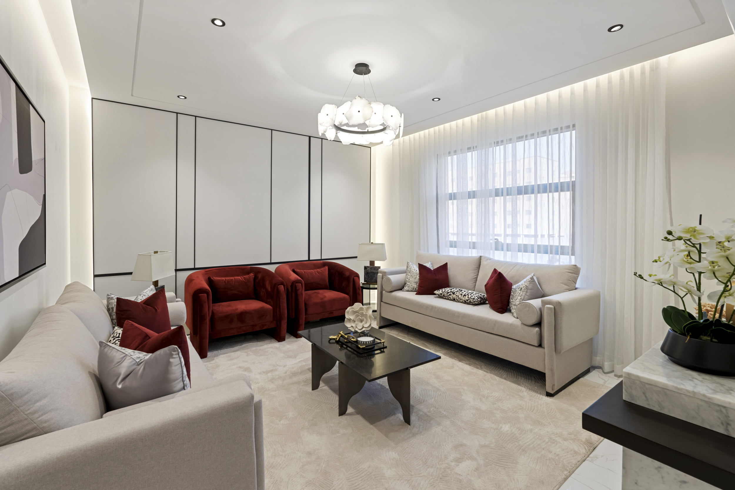spacious living room with creamy white sofa and red chairs