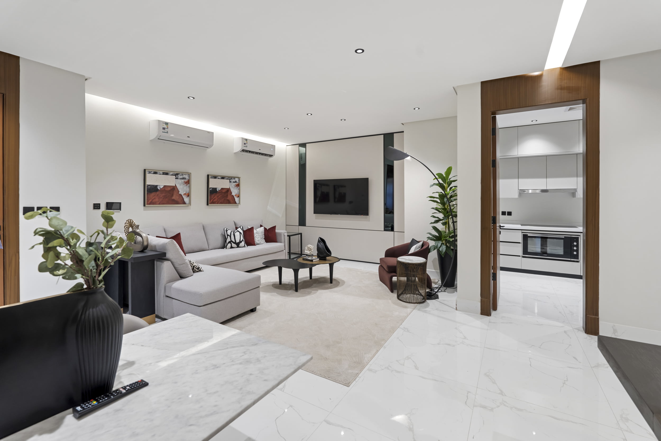 living room creamy white sofa and red pillows with large screen tv and wooden doors